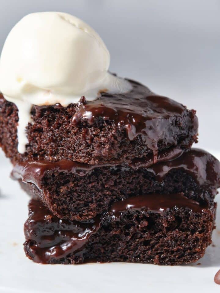 Several moist chocolate fudge cake slices with vanilla ice cream on top.