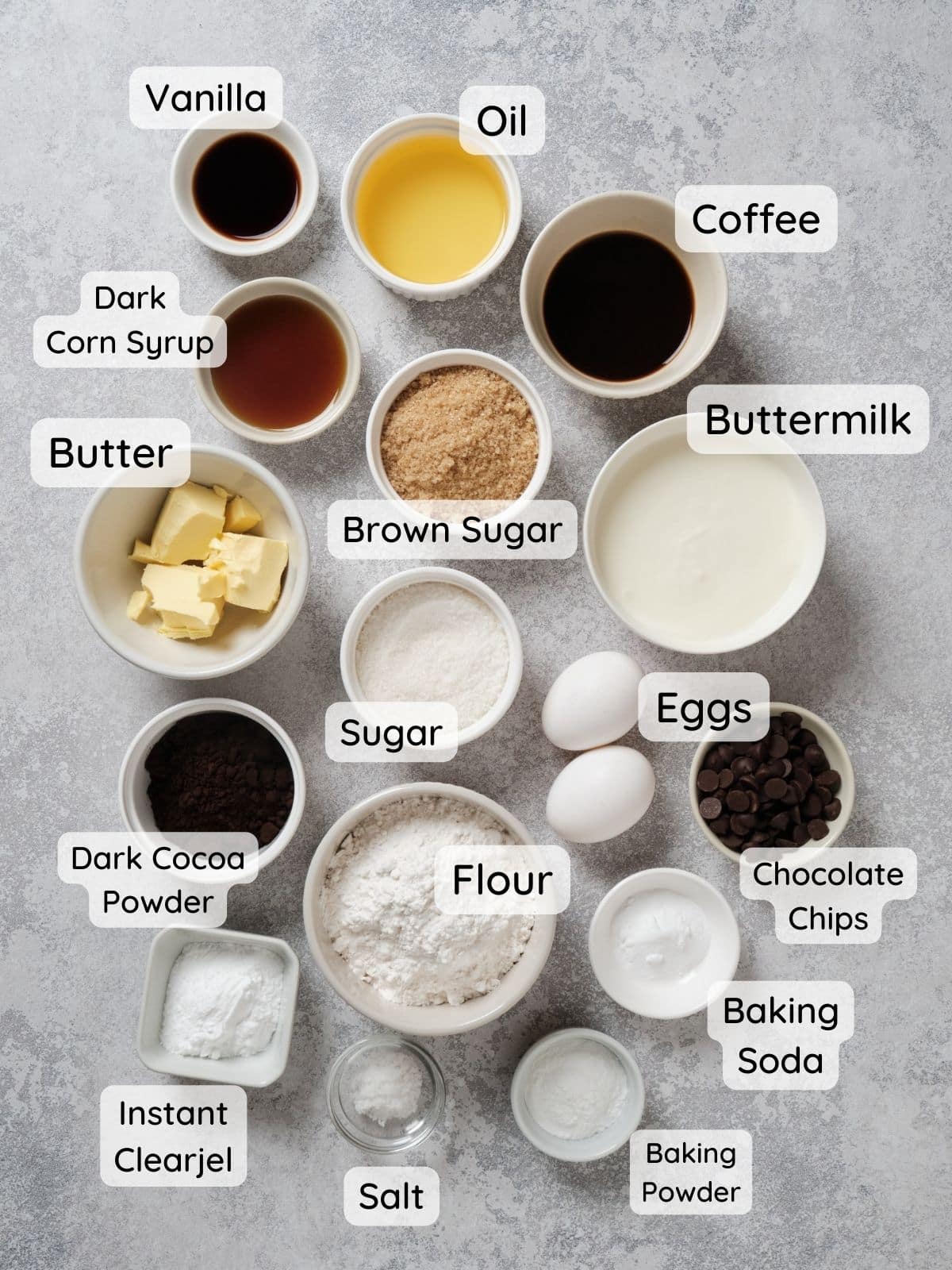 Caramel filled chocolate cupcake ingredients on a table, with the text "flour, sugar, brown sugar, baking powder, baking soda, salt, instant clearjel, dark cocoa powder, butter, eggs, buttermilk, coffee, dark corn syrup, vanilla."