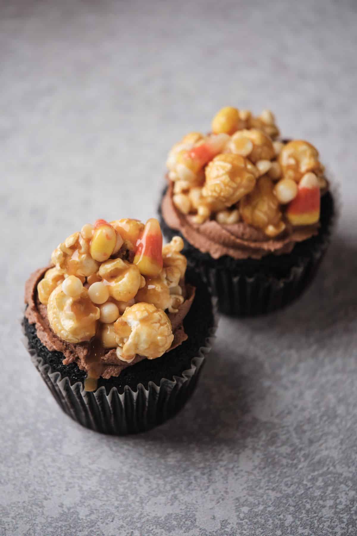 Two Caramel-filled cupcakes topped with caramel corn.