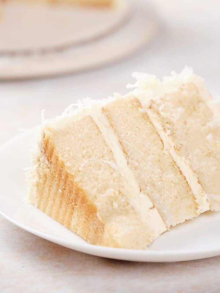 A moist slice of sour cream coconut poke cake on a plate.