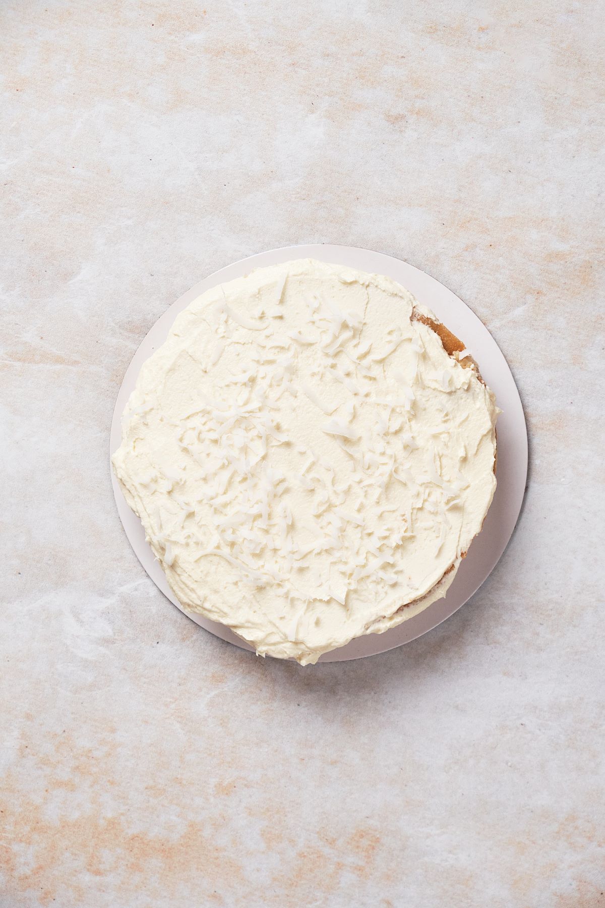 Layering the coconut cake with buttercream and coconut flakes.