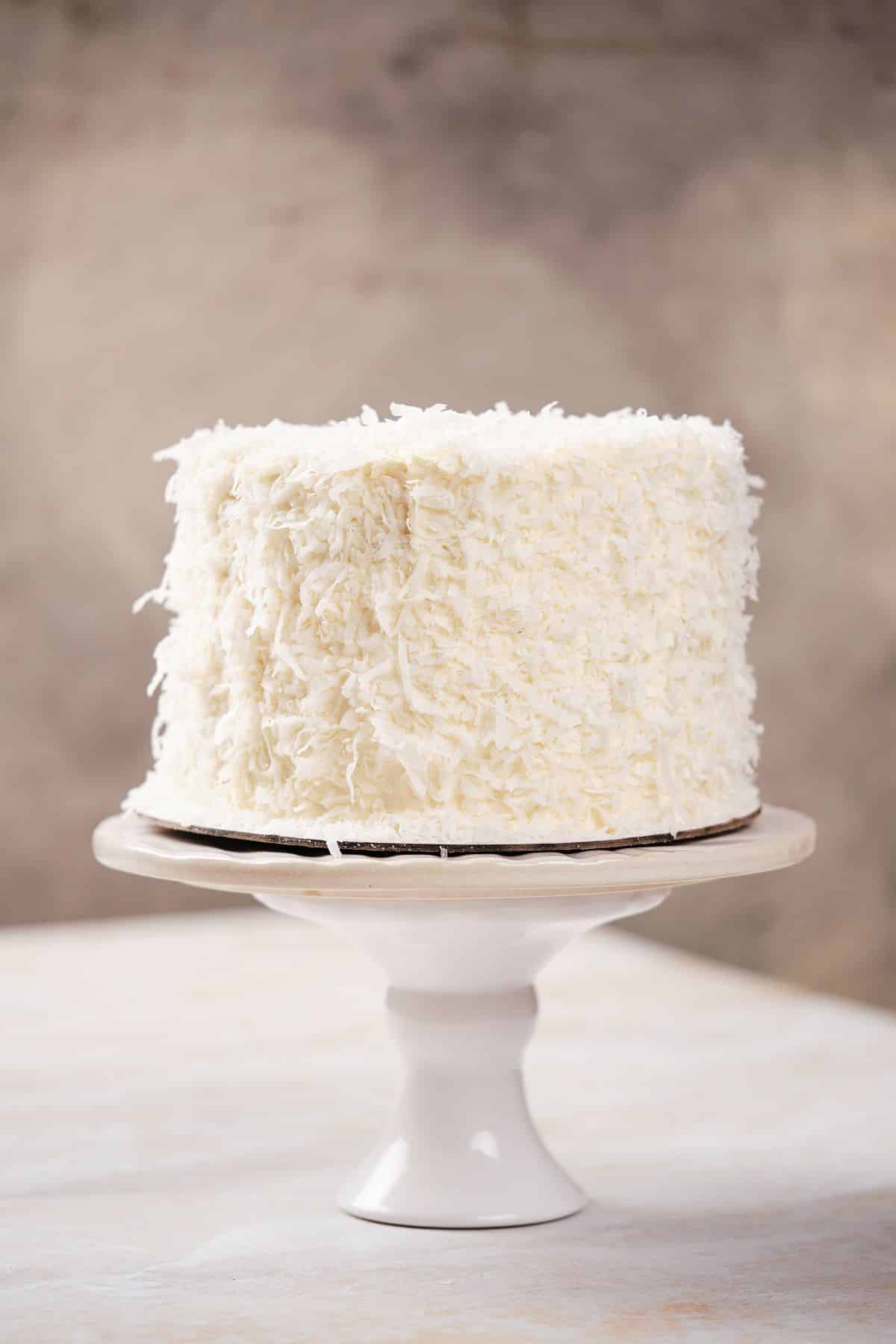 Coconut cream layer cake on a cake pedestal.