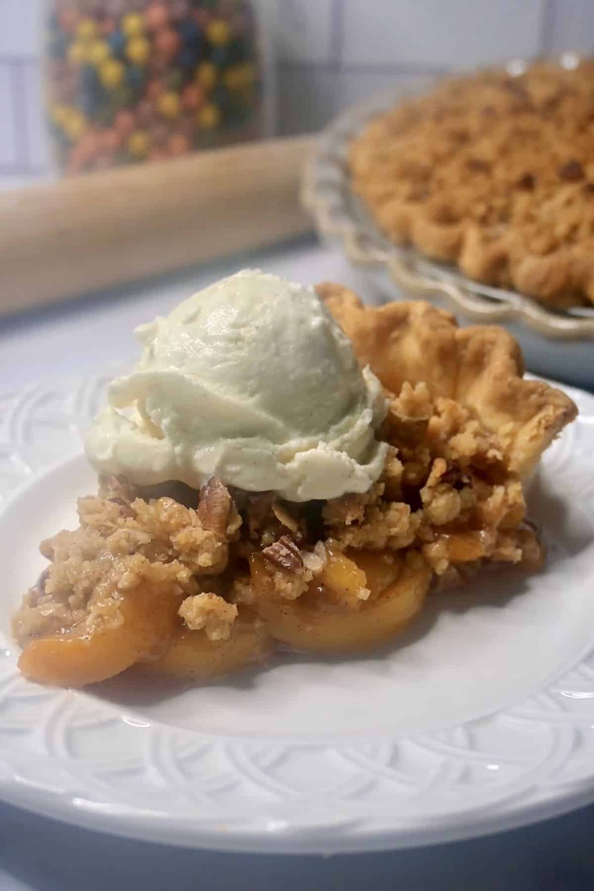 A slice of peach crumble pie on a plate.