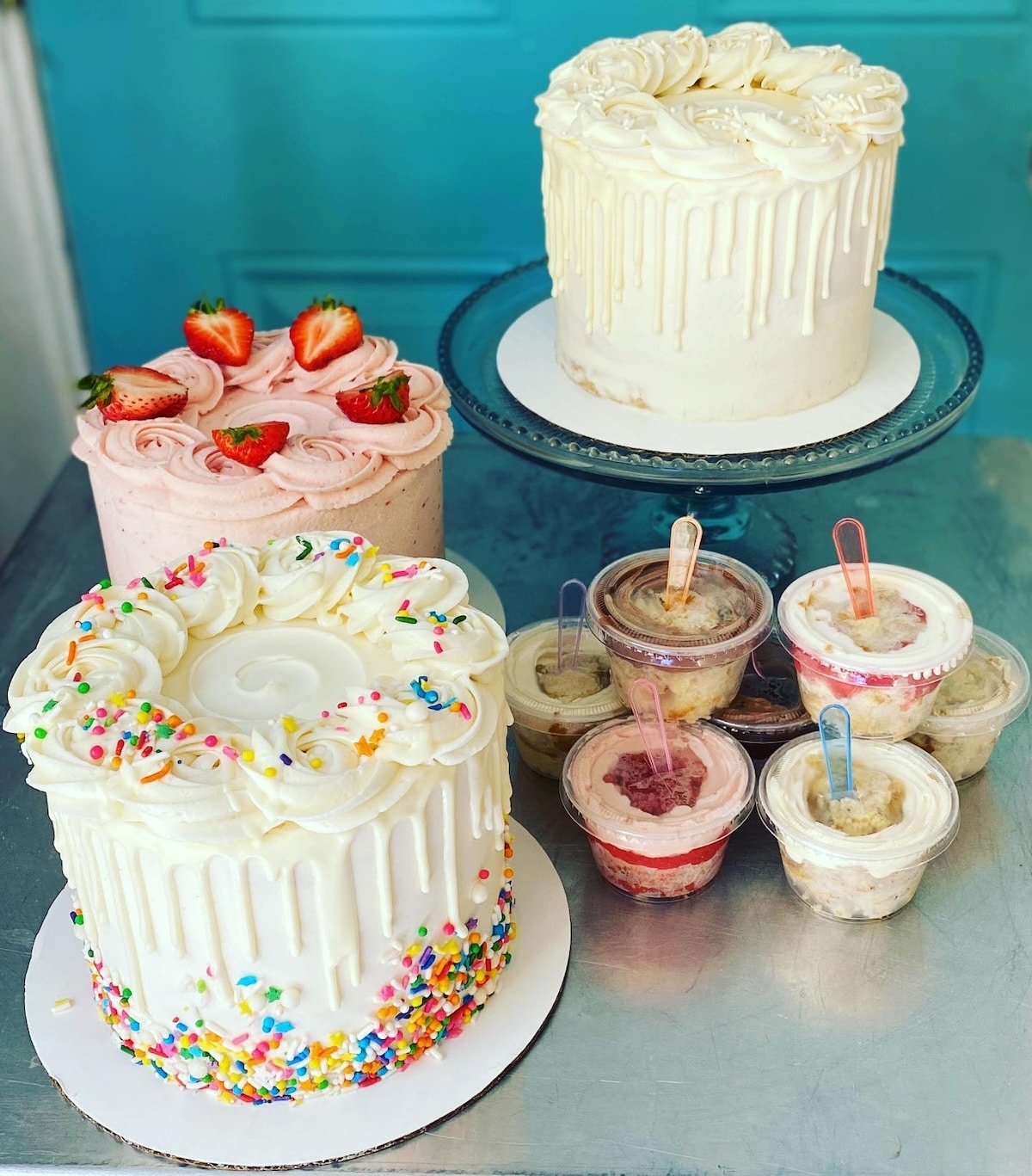 three layered cakes displayed next to mini plastic cake cups.