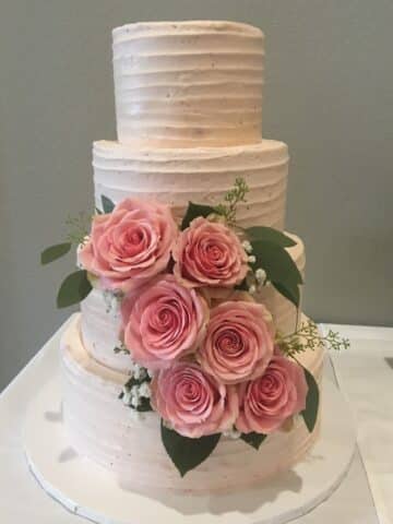 strawberry wedding cake with three layers and pink roses.