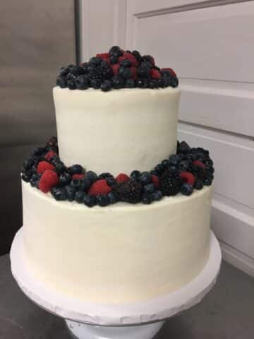 two tiered vanilla wedding cake with white vanilla frosting and fresh berries.