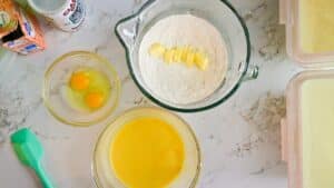 The orange almond cake dry ingredients and butter in a stand mixer bowl, the wet ingredients and orange zest in a separate bowl, and the eggs in a third small bowl.