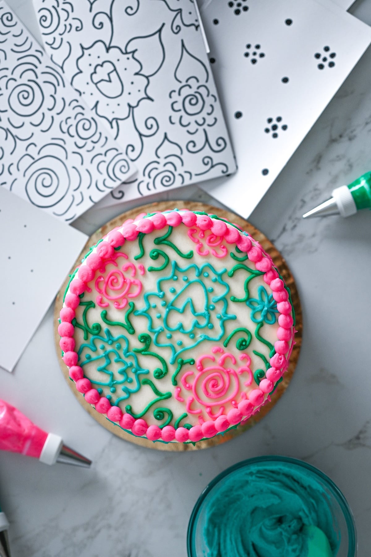 colorful cake with pink, blue and green icing next to printable cake decorating piping design templates.