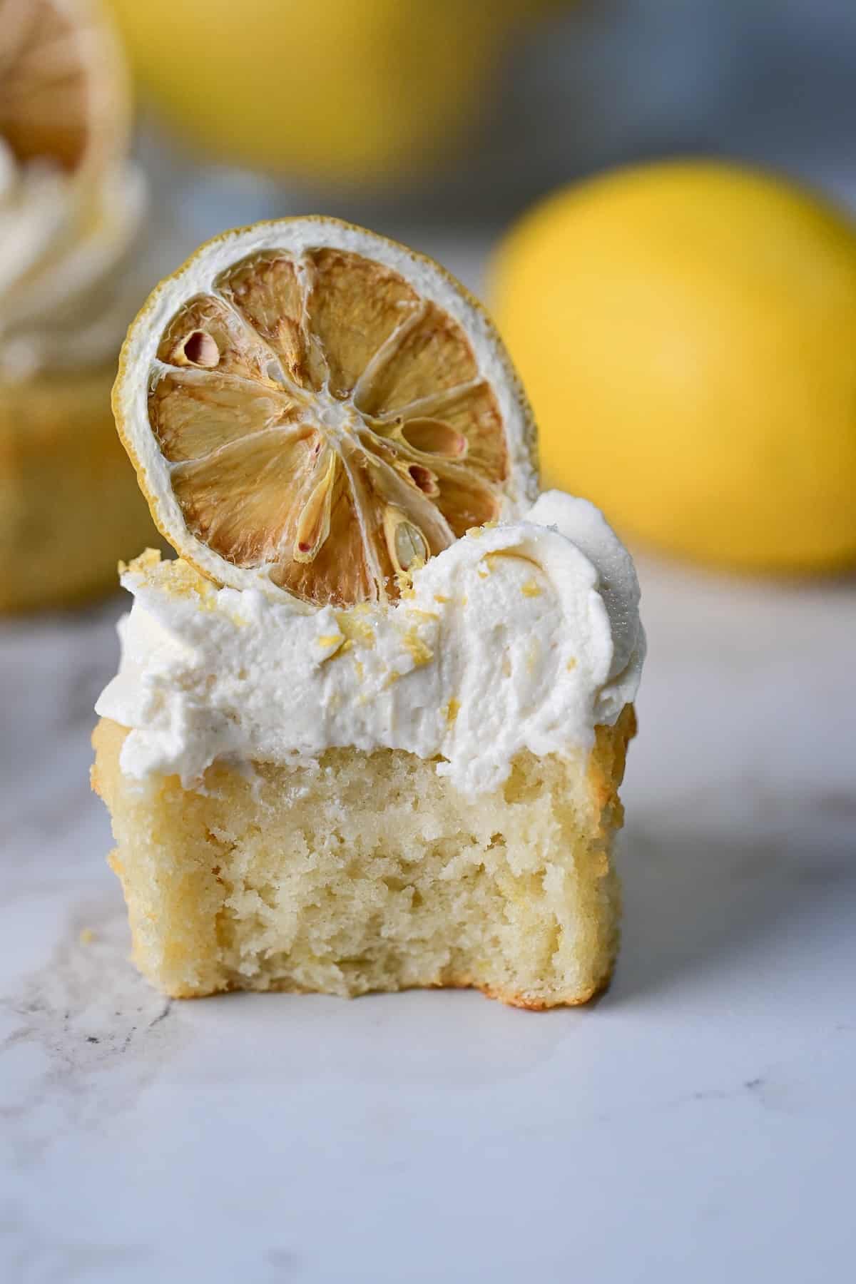 closeup view of lemon drizzle cupcake with a bite taken out of it.