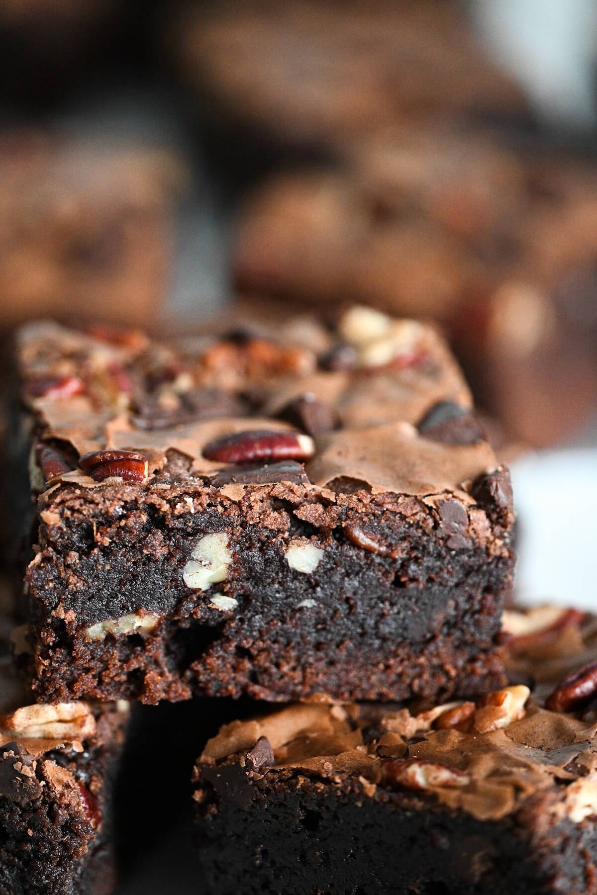 closeup view of a chewy bakery brownie with pecans and dark cocoa powder.