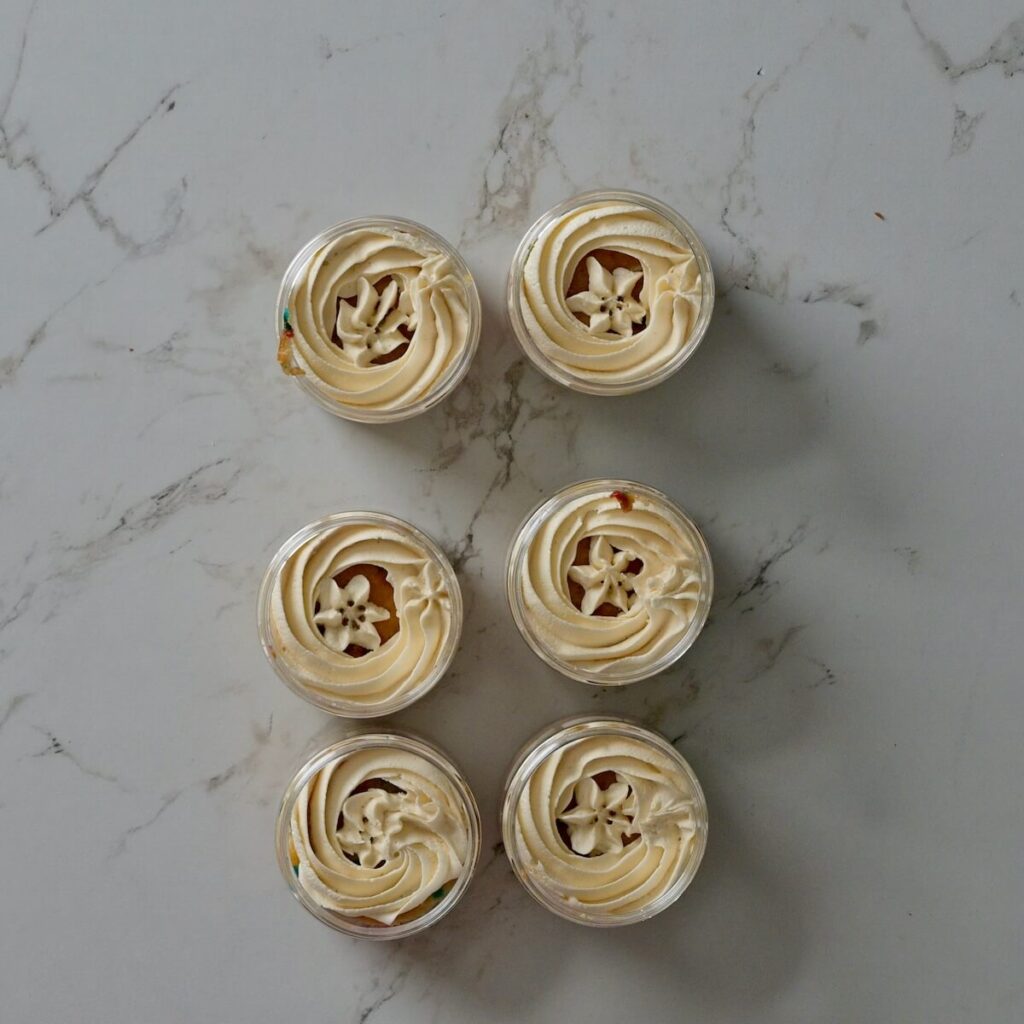 cakes in a jar with the first layer of frosting on top of the cake.