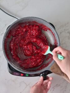 making raspberry compote in a pan for raspberry cake and frosting.