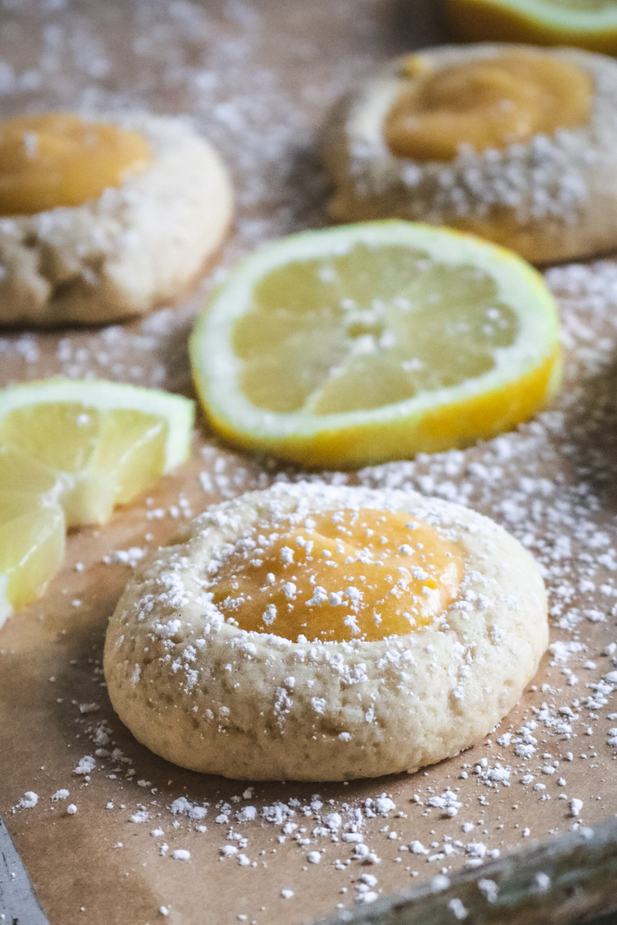 close up view of chewy lemon curd cookies sprinkled with powdered sugar.