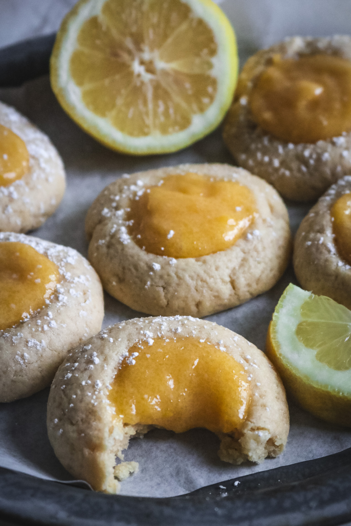 close up view of chewy lemon curd cookies with one w ith a bite taken out of it to show how tender the lemon curd is.