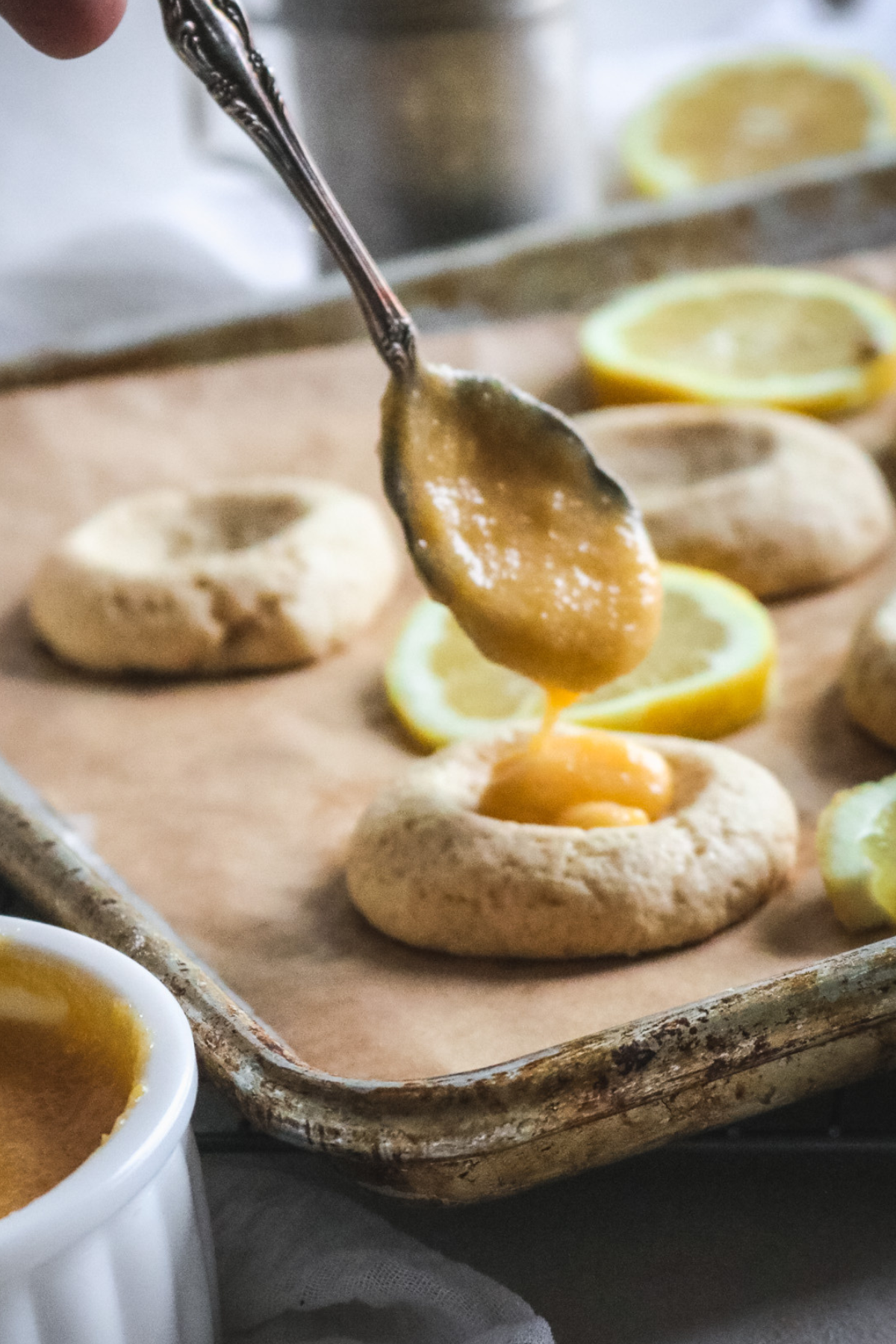 spooning lemon curd into freshly baked vanilla cookies to make lemon curd cookies.