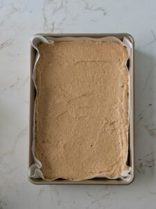 Applesauce cake batter spread evenly into a parchment-lined cake pan.