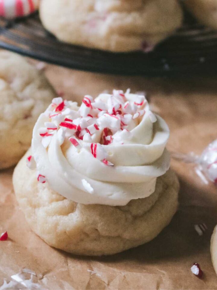 close up view of a peppermint sugar cookie topped with vanilla frosting and crushed peppermint candies.