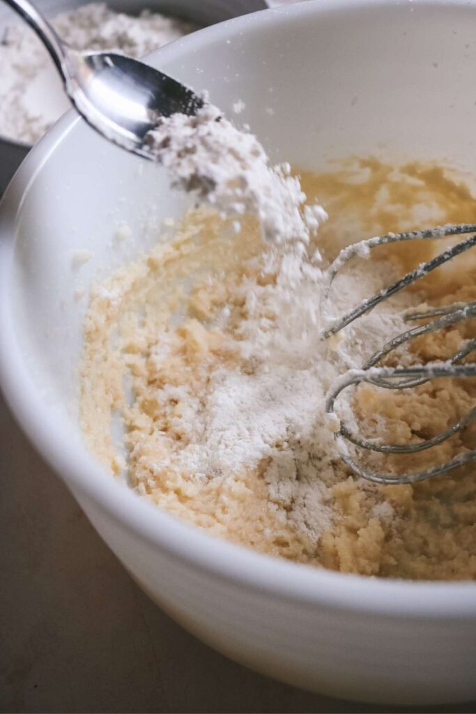 adding dry ingredients to peppermint sugar cookie dough.