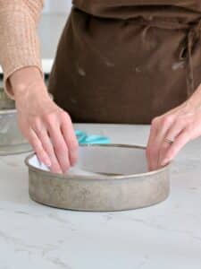 parchment paper lining the round cake pan for the cheesecake.