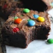 close up image of a thick, chewy m&m brownie with a bite out of it.