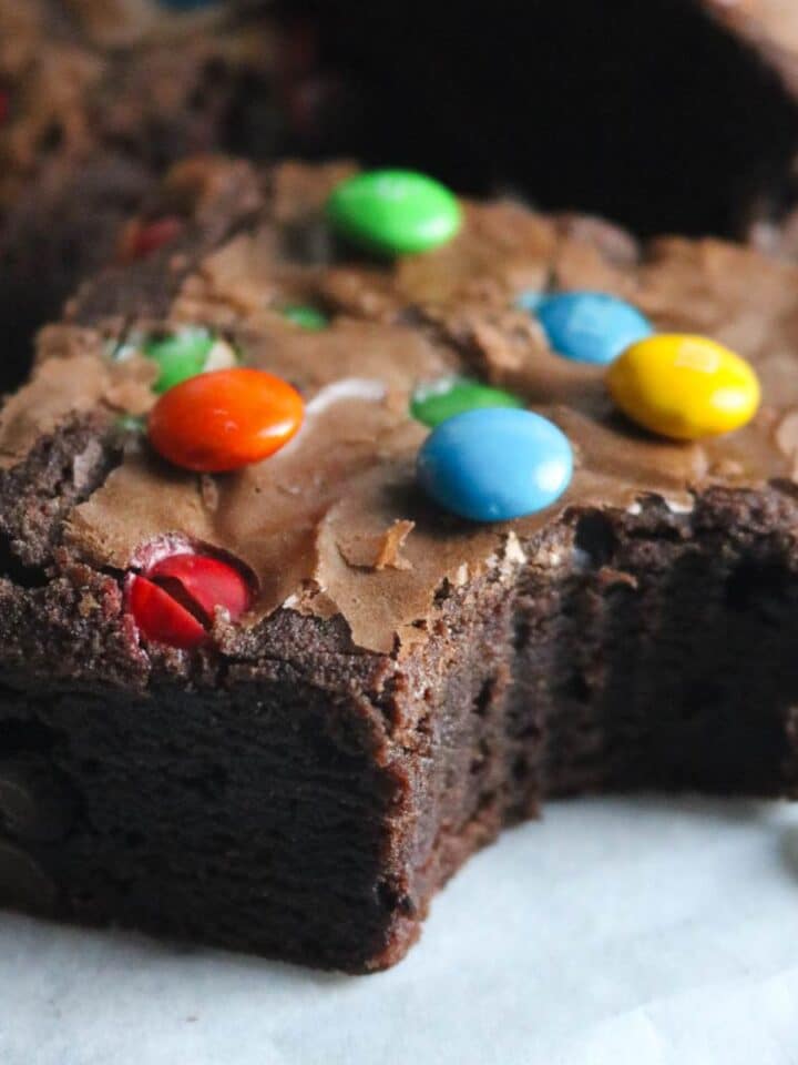close up image of a thick, chewy m&m brownie with a bite out of it.