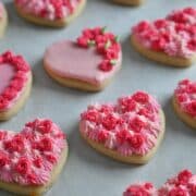 Soft Valentine heart cookies with thick buttercream frosting piped in shades of pint.