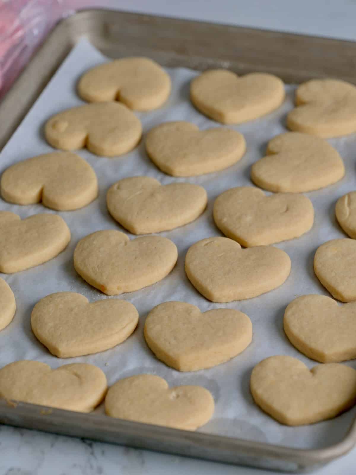 Thick soft heart sugar cookies on a baking tray.