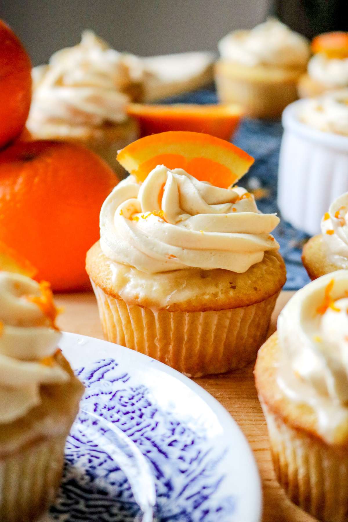 a moist orange cupcake topped with fluffy buttercream and sliced orange surrounded by other cupcakes.
