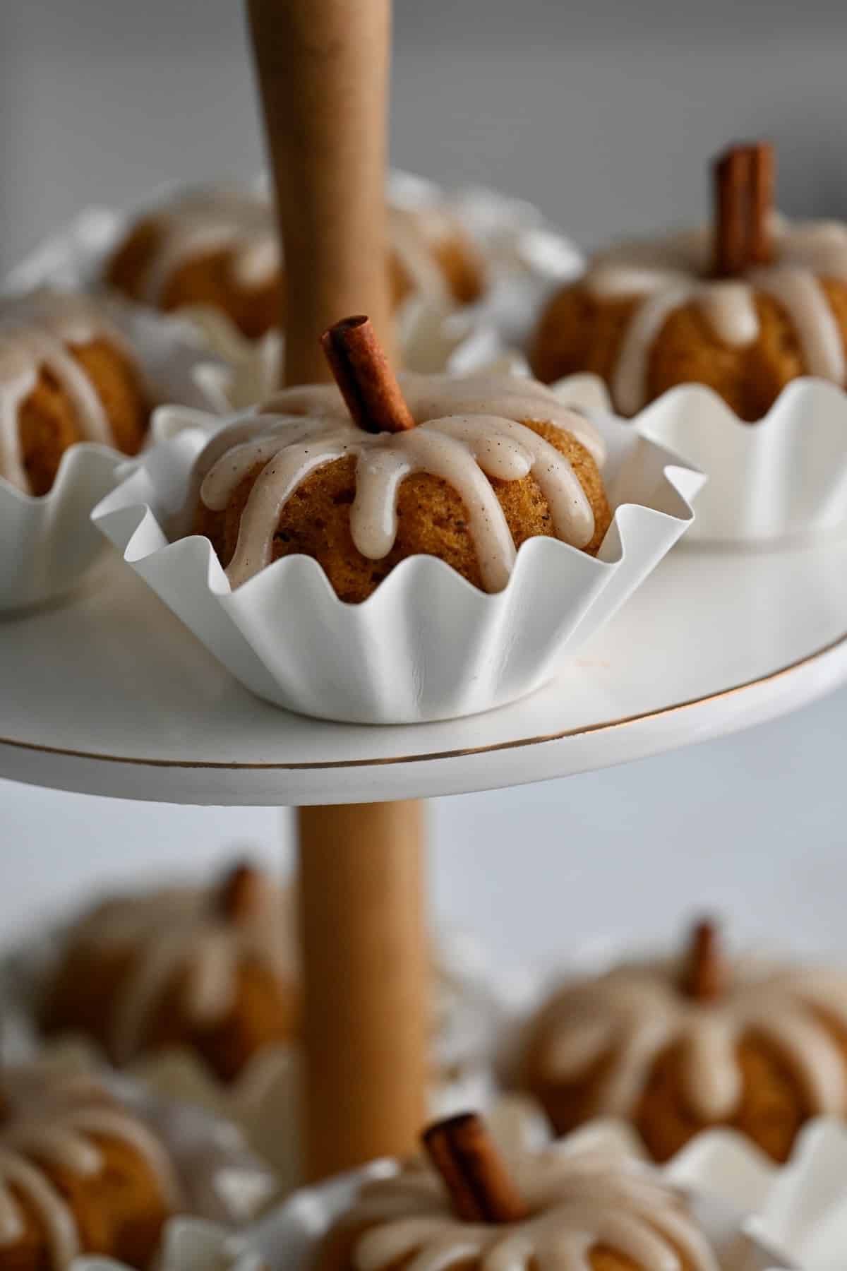 Close view of a glazed pumpkin mini bundt cake on the top tier of a dessert stand.